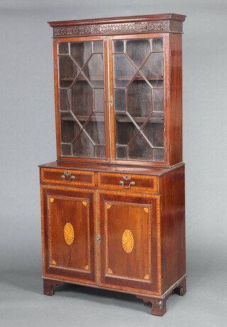 An Edwardian inlaid mahogany display cabinet on cabinet with moulded cornice and blind fret work frieze, fitted shelves enclosed by astragal glazed panelled doors, the crossbanded base fitted 2 long drawers above cupboard enclosed by panelled doors, raised on square supports 188cm h x 88cm w x 44cm d 