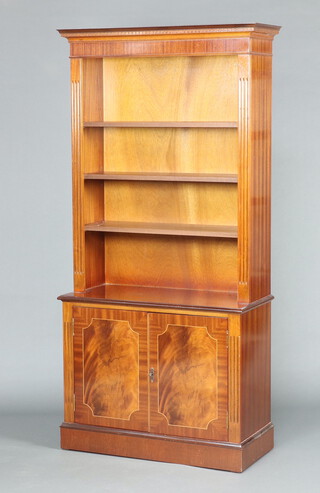 A Georgian style mahogany bookcase on cabinet with moulded and dentil cornice, fitted adjustable shelves, the base enclosed by panelled doors 185cm h x 88cm w x 39cm d 