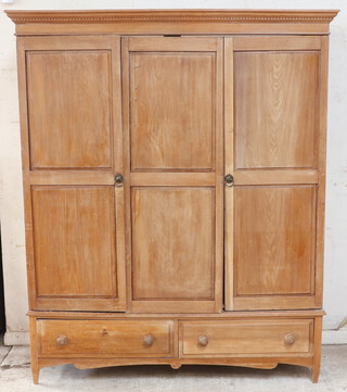 A 19th Century pine triple wardrobe with moulded and dentil cornice, enclosed by a pair of panelled doors, the base fitted 2 drawers, 210cm h x 177cm w x 66cm d 