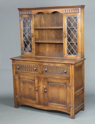 A carved oak dresser the raised back with moulded cornice fitted 3 shelves flanked by cupboards enclosed by lead glazed panelled doors, the base with 2 drawers above double cupboard 174cm h x 121cm w x 45cm d 