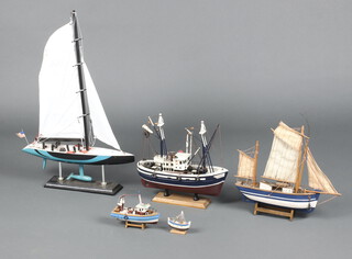 A wooden model of an American racing yacht boat 60cm h x 39cm w x 8cm d together with 4 models of fishing boats  