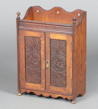 An Edwardian carved oak hanging smoker's cabinet, upper section with 3/4 gallery, fitted 2 drawers above a shelf enclosed by panelled doors and raised on bun feet 46cm h x 32cm w x 17cm d 