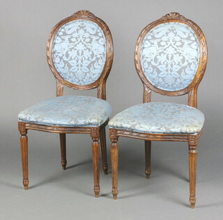 A pair of French style carved beech salon chairs, the seats and backs upholstered in blue material raised on turned and fluted supports 100cm h x 50cm w x 45cm d (seat 30cm x 28cm) 