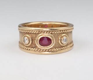 A 9ct yellow gold Etruscan style ring set with an oval cut ruby and 2 brilliant cut diamonds, the ruby 0.40ct, the brilliant cut diamonds each 0.07, 7.8 grams, size P 