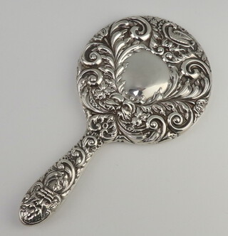 A Victorian style repousse silver backed hand mirror with vacant cartouche, mask and scroll decoration Birmingham 1934 