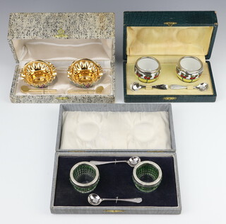 A cased pair of silver mounted green glass condiments with plated spoons, 2 other cased condiment sets 