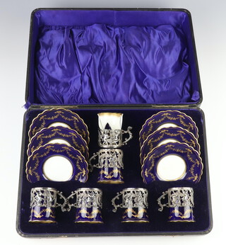 An Edwardian coffee set with blue and gilt decoration comprising 6 cups and 6 saucers (1 cup a/f) with Edwardian pierced repousse silver mounted holders decorated with cherubs Birmingham 1907, in a fitted case 