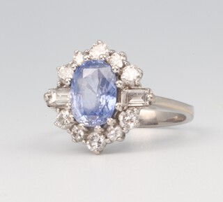 A white metal oval cornflower sapphire and baguette and brilliant cut diamond cluster ring, the sapphire 1.25ct, the diamonds 0.5ct, size D 1/2 4.2 grams 