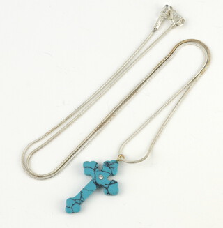 A turquoise cross pendant on a silver chain 