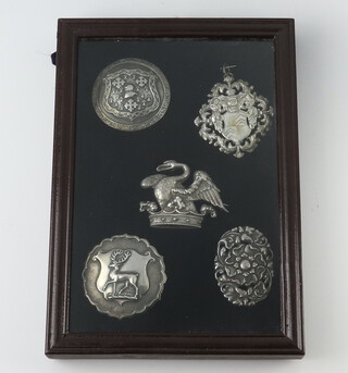 Five white metal repousse badges, framed