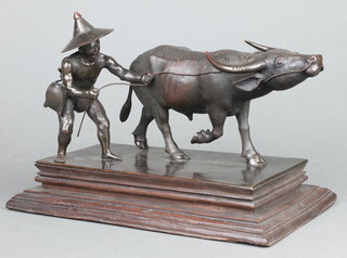 A Burmese bronze group of an Oriental farmer with water buffalo on a wooden base, stamped Mgsan Wa Pegu 26cm 