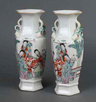 A pair of Chinese famille rose hexagonal vases with leaf handles decorated with figures on pavilion terraces, red character mark to base 23cm