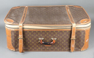 Louis Vuitton, a suitcase with straps 28cm x 58cm x 53cm, the interior with paper label marked Manufactured in the USA under licence to a French Company 