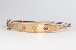 A 9ct yellow gold diamond and ruby bangle, the 3 diamonds 0.20ct, the 2 rubies 0.30ct, 50mm diam., 7 grams 