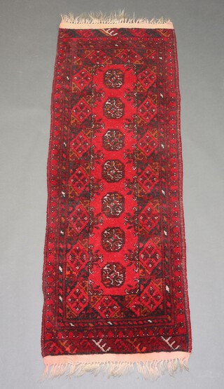 A red and black ground Afghan runner with 7 octagons to the centre 143cm x 54cm 