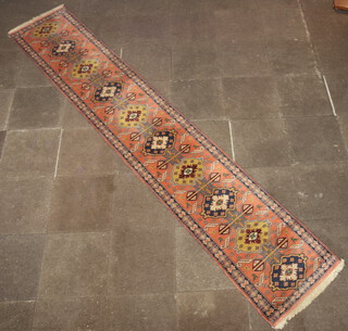 An orange, brown and blue ground Persian runner with 10 stylised medallions to the centre within a multi row border 385cm x 70cm 