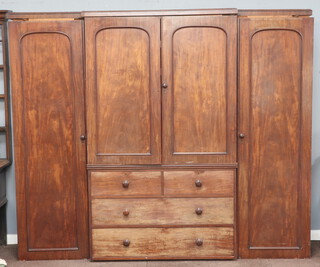 A Victorian mahogany triple breakfront wardrobe with moulded cornice, the centre upper section fitted 5 trays enclosed by panelled door, the base fitted 2 short and 2 long drawers flanked by hanging cupboards enclosed by arched panelled doors, the centre section marked VR  206cm h x 248cm w x 56cm d  
