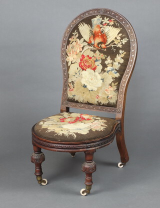 A Victorian carved mahogany show frame nursing chair with Berlin woodwork embroidered back and seat decorated a bird amidst flowers, raised on turned supports 102cm h x 51cm w x 50cm d (seat 31cm x 36cm) 