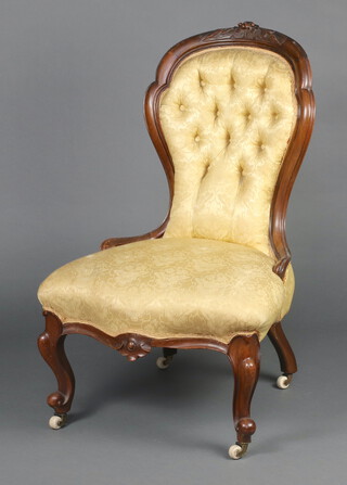 A Victorian carved mahogany show frame nursing chair upholstered in buttoned yellow material, seat of serpentine outline, raised on cabriole supports 91cm h x 57cm w x 50cm d (seat 28cm x 30cm) 
