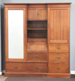 A Victorian mahogany break front double wardrobe with shaped and moulded cornice, the centre hanging section enclosed by panelled doors above recess fitted 2 short drawers above bureau with fall front above a further short drawers, flanked by a cupboard fitted trays enclosed by a panelled door above 3 long drawers, raised on a platform base 202cm h x 187cm w x 56cm d 