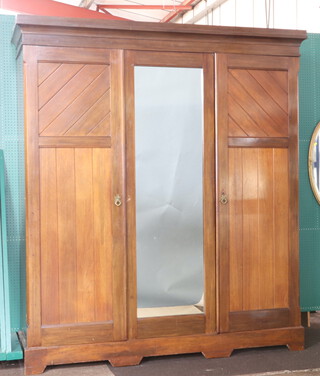 A Victorian triple wardrobe with moulded cornice with hanging space enclosed by panelled door, the centre section fitted a cupboard and 3 shelves above 2 short and 2 long drawers enclosed by mirror panelled door and panelled door 212cm h x 185cm w x 59cm d 