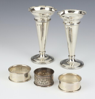 A pair of Edwardian tapered silver posy vases, London 1909, 13cm and 3 silver napkin rings, 256 grams 