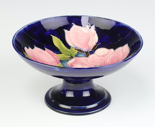 A Moorcroft blue glazed pedestal bowl with Magnolia decoration, on a spreading foot with signature to base 10cm x 18cm 