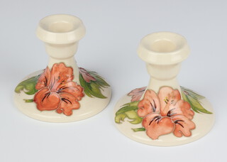 A pair of  Moorcroft white glazed candlesticks of waisted form decorated the hibiscus pattern, base with paper Moorcroft label 8cm  