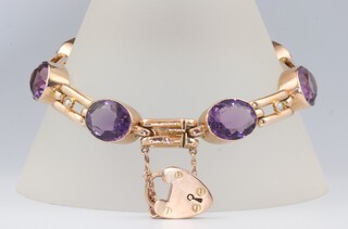 A 9ct yellow gold bracelet set with 7 oval cut amethysts each 12mm x 9mm and 6 seed pearls, having a safety link with gold padlock clasp 17.5 grams, 18cm 