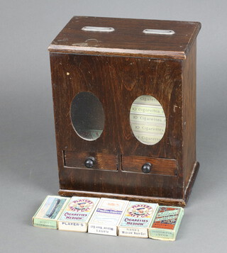 A 1920's table top cigarette vending machine contained in an oak case, the base fitted 2 drawers containing 4 empty packets of Will's woodbine cigarettes and 10 empty packets of Player's Navy Cut cigarettes, 26cm h x 21cm w x 13cm d 