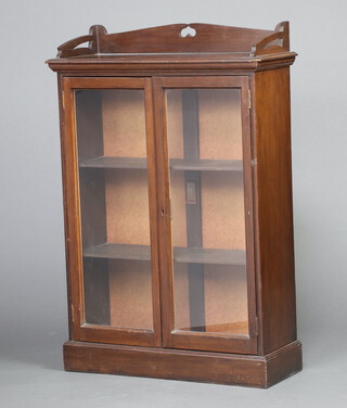 An Art Nouveau, Liberty style mahogany display cabinet with 3/4 gallery, the interior fitted shelves enclosed by glazed panelled doors 101cm h x 70cm w x 26cm d 