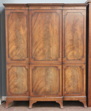 A Georgian style mahogany triple breakfront wardrobe with moulded cornice having Grecian key decoration, the centre section with hanging bar flanked by shelved cupboards, raised on bracket feet 200cm h x 150cm w x 60cm d 