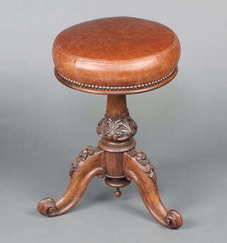 A Victorian carved rosewood piano stool, the seat upholstered in brown leather, raised on a carved turned baluster and tripod base 50cm x 34cm diam. 