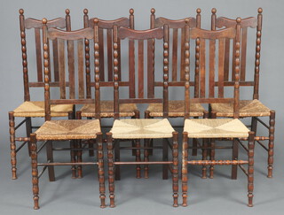 A set of 7 Art Nouveau oak stick and rail back dining chairs with woven rush seats, raised on bobbin turned supports 110cm h x 42cm w x 40cm d (seats 27cm x 23cm) 