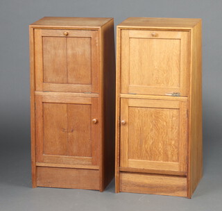 A G-Plan style pair of 1950's light oak wedge shape bedside cabinets with fall fronts revealing fitted interiors above cupboard enclosed by a panelled door 84cm h x 38cm w x 28cm d (1 with damage to fall front, sun bleached, ring and contact marks in places) 