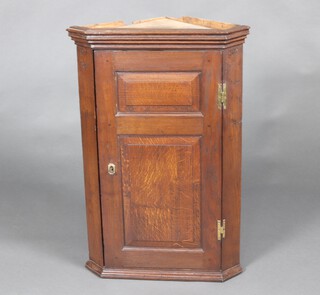 An 18th/19th Century oak hanging corner cabinet with moulded cornice, interior fitted shelves enclosed by panelled door 94cm h x 63cm w x 44cm d 