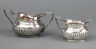 A Victorian silver twin handled sugar bowl with demi-reeded decoration together with a matching cream jug Sheffield 1897, 236 grams 