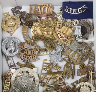 A collection of metal shoulder titles, cap badges 