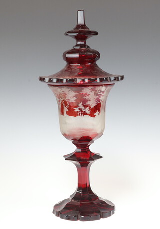 A 19th Century Bohemian red overlay glass jar and cover decorated stags in wooded landscape, raised on a shaped base 47cm 