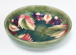 A William Moorcroft green ground bowl with grape and leaf decoration, circa 1930, the base with impressed Moorcroft mark and signature 22cm   