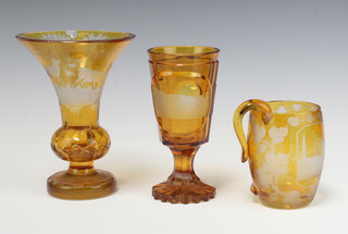 A 19th Century Bohemian amber glass overlay goblet decorated a town scene, raised on a spreading foot 16cm (chip to base), ditto vase decorated stags 17cm (heavily chipped to rim) and a matching tankard 10cm (handle f) 