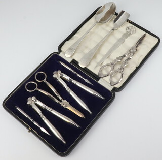 A cased set of silver plated grape scissors, 2 pairs of nut crackers and 2 nut picks, together with a Maltese silver paper knife, silver plated stilton scoop, ditto moustache spoon and grape scissors