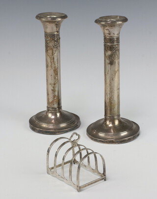 A silver 5 bar toast rack Chester 1923, 39 grams, together with a pair of Edwardian embossed silver candlesticks London 1900 18cm