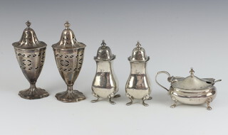 A pair of Georgian style oval pierced silver peppers London 1940 and 1941 complete with blue glass liners, a 3 piece silver condiment set with 2 peppers and mustard Birmingham 1905 and 1906, 294 grams 