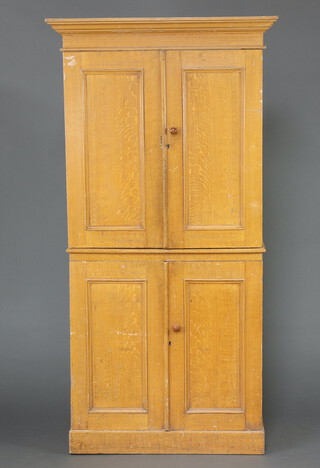 A Victorian pine scumble painted press cabinet with moulded cornice, both sections fitted shelves enclosed by panelled doors, raised on a platform base 202cm h x 103cm w x 57cm d 