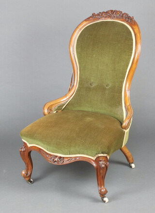 A Victorian carved walnut show frame nursing chair, the seat and back upholstered in green material, raised on cabriole supports 98cm h x 57cm w x 60cm d (seat 32cm x 35cm) 