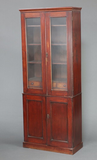 A Victorian mahogany cabinet on cabinet, the upper section fitted shelves above an arrangement of 5 drawers enclosed by glazed panelled doors, the base enclosed by a panelled door 199cm h x 79cm x 36cm d 