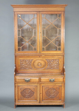 A Victorian carved oak secretaire bookcase with moulded cornice, the shelved interior enclosed by astragal glazed panelled door, the fall front revealing a fitted interior with stationery rack to the centre, pigeon holes and 2 drawers, above 2 drawers and cupboard enclosed by a panelled door 227cm h x 123cm w x 41cm d 