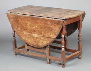 An 18th Century oak oval drop flap gate leg dining table fitted a drawer raised on turned and block supports with box framed stretcher 72cm h x 112cm x 53cm