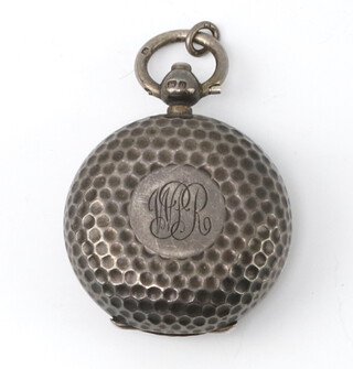 A silver sovereign holder in the form of a golf ball with engraved monogram Birmingham 1913, containing a brass coin 